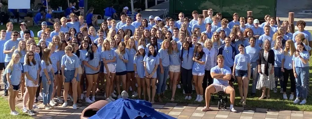 A large group of young people wearing blue shirts at a college event
